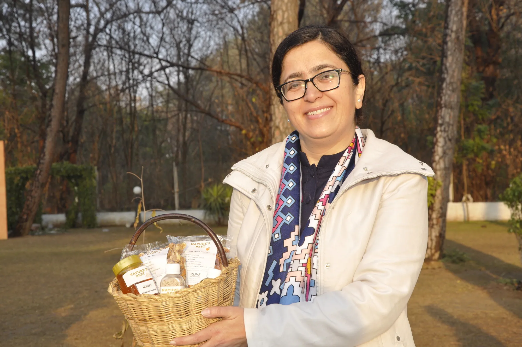 A woman smiles while holding a basket filled with small gifts.